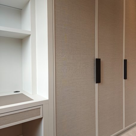 White Grey wardrobe and desk with wallpapered doors. Interior featuring light beige cabinetry with black handles and a small open shelf.