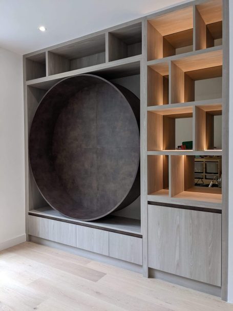Tivoli and bronze circular seating, open shelving with LED's Modern interior featuring a circular wooden shelf and illuminated cubical compartments.