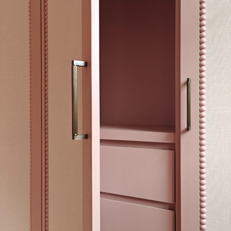 Antique rose finish wardrobes featuring elegant arched panel detailing, integrated top ventilation grilles, bobble bead details. Modern pink cabinet with two handles and a minimalist design.