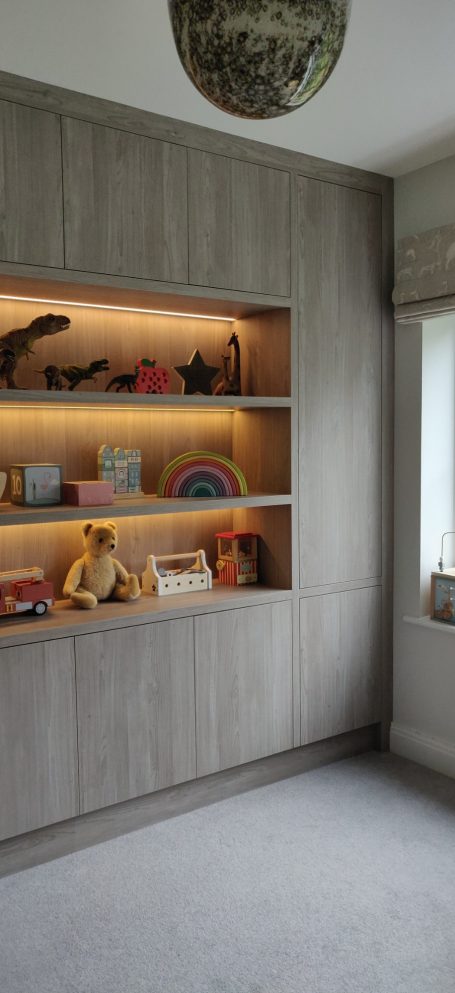 Grey Nordic Wood open shelving with LED's. Surrounding storage A modern room with a wooden shelf displaying various toys and decorative items.