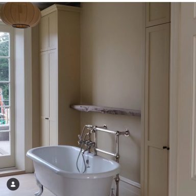 Hand painted Linen Cupboards. Modern bathroom with a freestanding bathtub and light wooden shelf against a neutral wall.