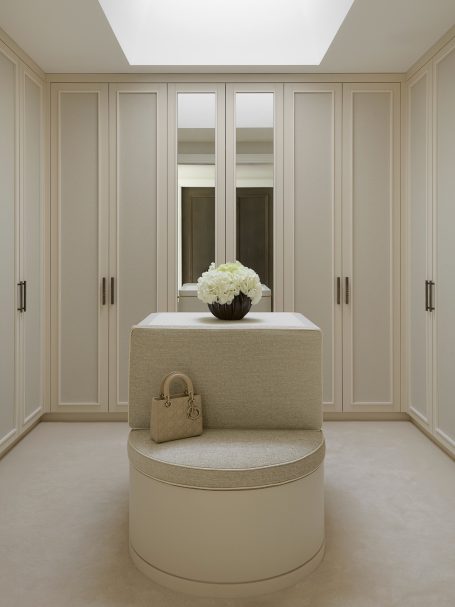 Cremé Beige walk-in dressing room with island Modern dressing room with built-in cabinets, a central island, and a floral arrangement.