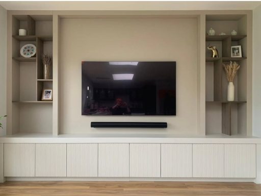 Angora Grey Tv panel with Bronze edged shelving and lower ribbed door storage. Modern living room with a wall-mounted TV and shelves for decor.
