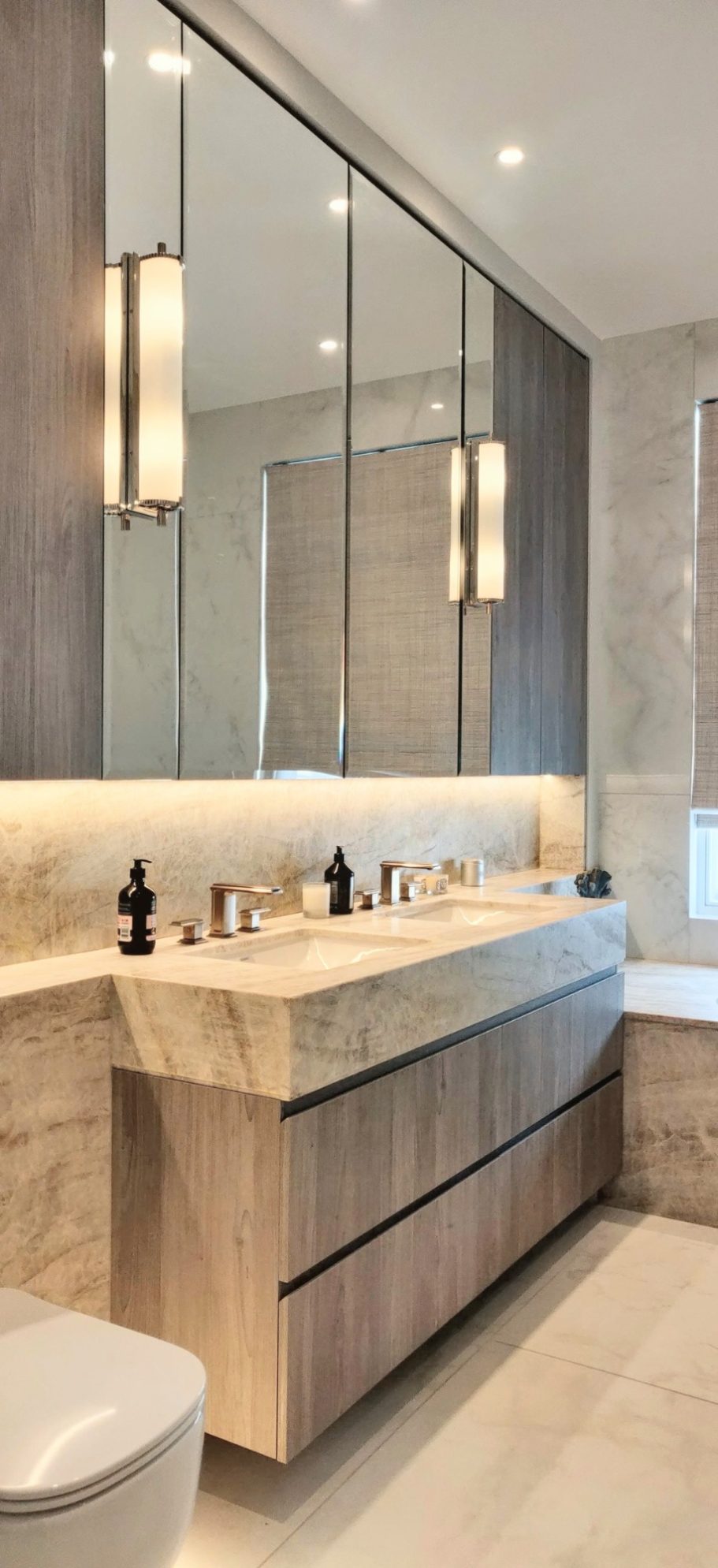 Grey Nordic four drawer vanity with mirrored wall cabinet. Modern bathroom with a light wood vanity, marble accents, and a large mirror.