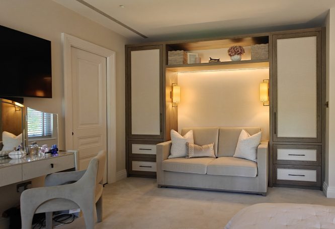 Brown orleans oak finish with wallpapered panels and bobble beading detail. Modern bedroom featuring a grey sofa, decorative wall lighting, and a stylish desk.