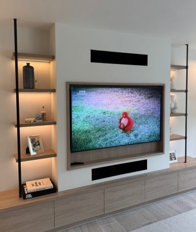 Bleached Cuneo Oak low drawers and floating shelves with LED's A modern living room with a TV displaying a cartoon character, surrounded by shelving.