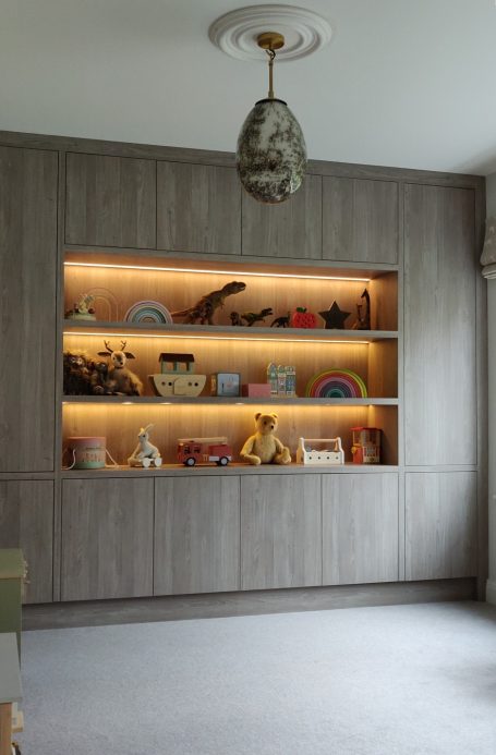 Grey Nordic Wood open shelving with LED's. Surrounding storage A modern room with a wooden shelf displaying various toys and decorative items.