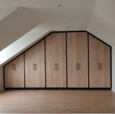 Modern room with angled ceiling and wooden storage cabinets along the wall.