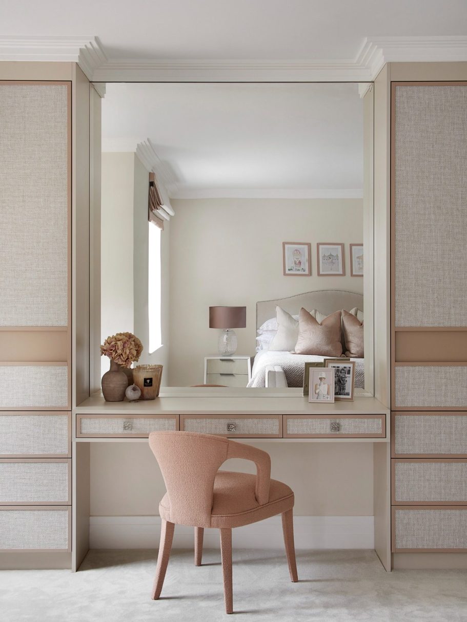 Sand Beige dressing room. Doors with integrated finger pull. A soft-hued room with a mirror, a chair, and a neatly made bed in the background.