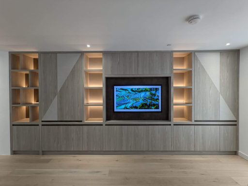 Tivoli and Nadir open shelving and lower storage Modern living room featuring a sleek cabinet with built-in TV and illuminated shelves.