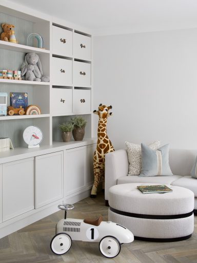 Grey White storage with sliding doors and open display shelving Bright playroom featuring a white sofa, plush toys, and a giraffe beside a toy car.