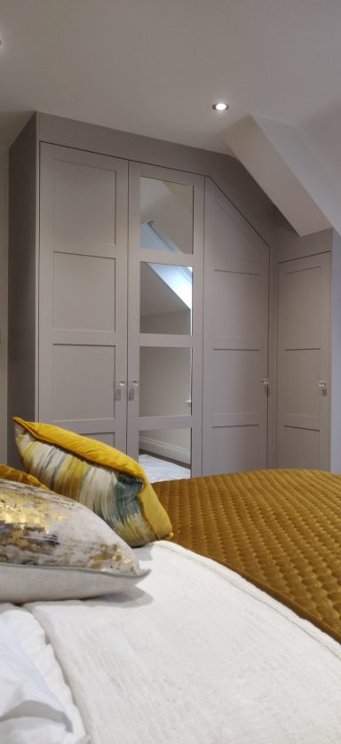 Cashmere Grey corner wardrobe Modern bedroom with a yellow bedspread and fitted wardrobes.