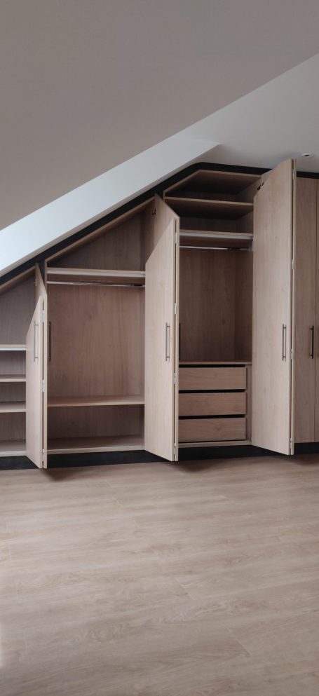 Natural Kendal Oak fitted wardrobe interior Stylish corner wardrobe with shelves and drawers, featuring an open door.