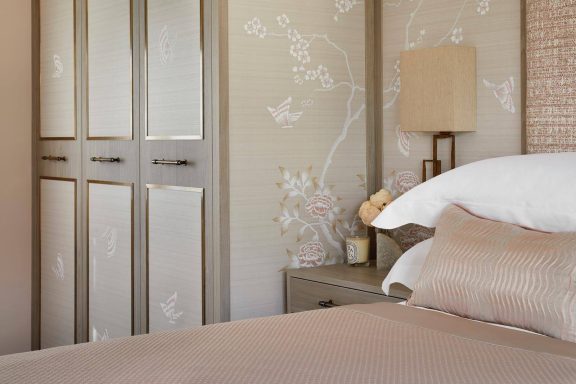 Nordic Grey wardrobe with wallpapered doors Neutral-toned bedroom with a bedside lamp and floral wallpaper.