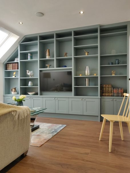 Fijord Green display shelving with central TV panel A modern living room with a light blue shelving unit and wooden flooring.