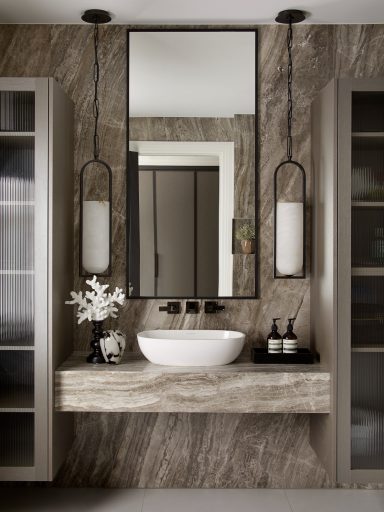 Xylo Eris wall cabinets with ribbed glass doors. Modern bathroom with a stone sink and elegant mirror, featuring stylish lighting and decor.
